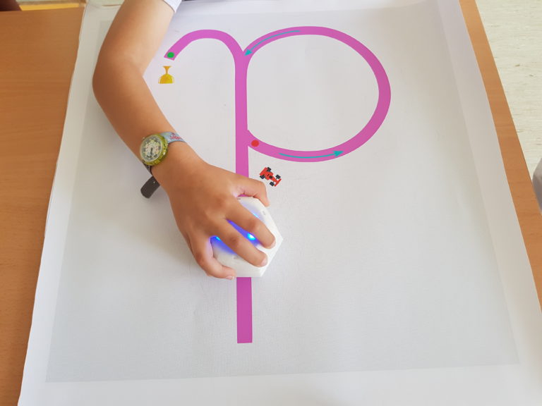 A kid uses the Cellulo robot to draw the letter D