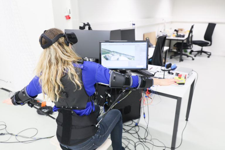 Picture of a woman wearing an exosuit and flying a drone virtually