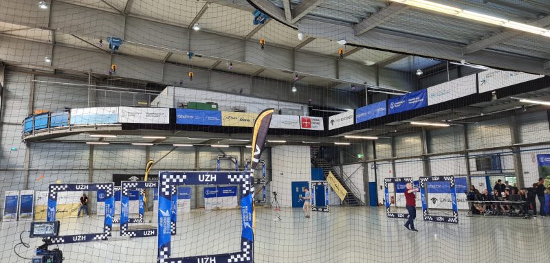 The picture shows a large arena protected by a net and with several obstacles to be passed by drones.